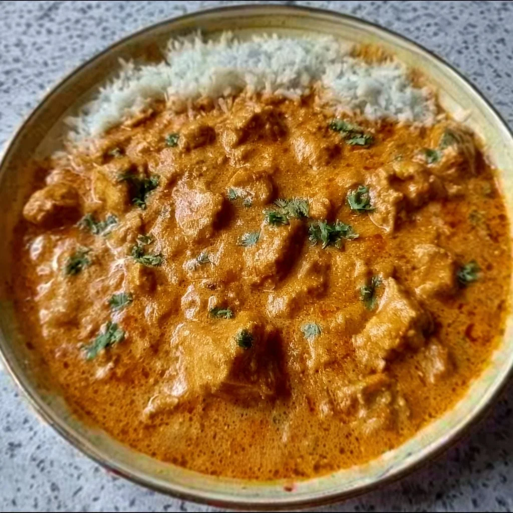 Delicious homemade butter chicken served with rice and garnish.